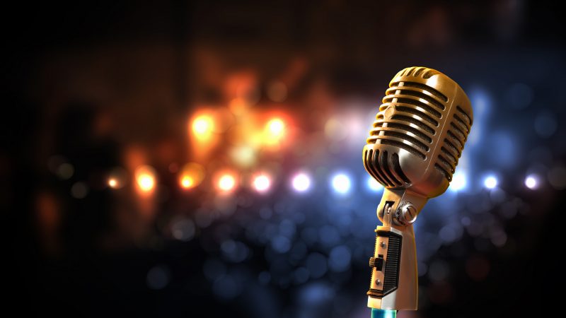 Single retro microphone against colourful background with lights
